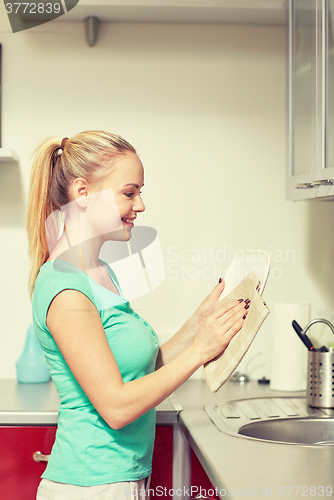 Image of happy woman wiping dishes at home kitchen