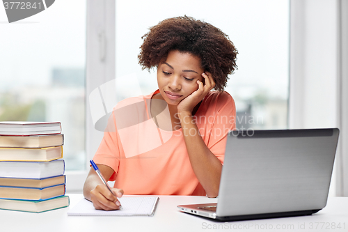 Image of bored african american woman doing homework home