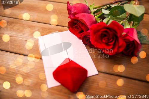 Image of close up of gift box, red roses and greeting card