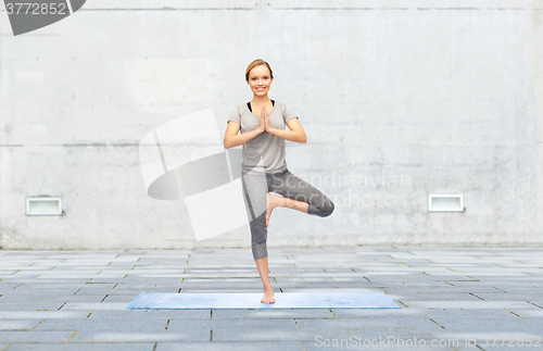 Image of woman making yoga in tree pose on mat