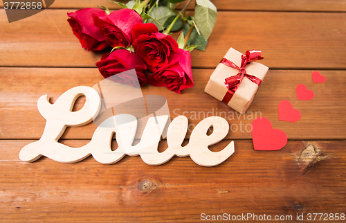 Image of close up of gift, word love, red roses and hearts