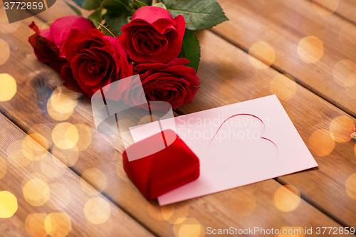 Image of close up of gift box, red roses and greeting card