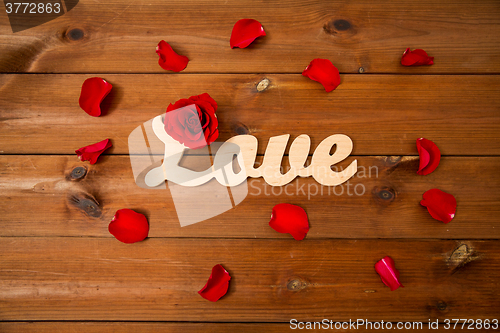 Image of close up of word love cutout with red rose on wood