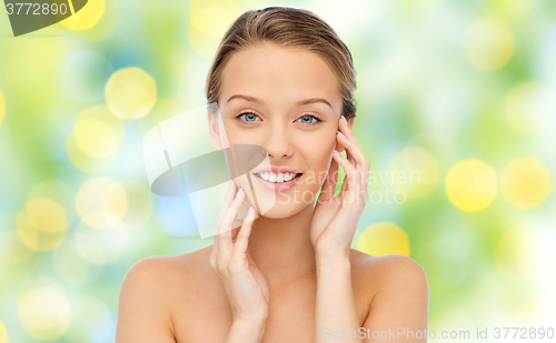 Image of smiling young woman touching her face