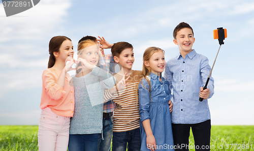 Image of happy children with smartphone and selfie stick