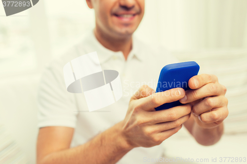 Image of close up of happy man with smartphone at home