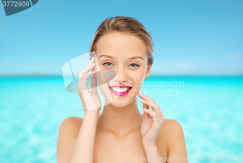 Image of smiling young woman with pink lipstick on lips