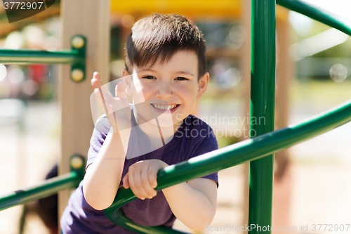 Image of happy little boy climbing on children playground