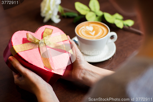 Image of close up of hands holding heart shaped gift box