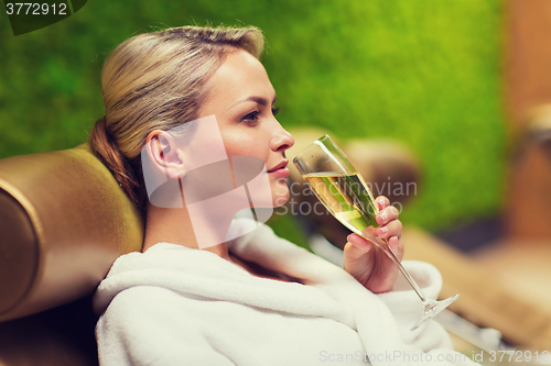 Image of beautiful young woman drinking champagne at spa