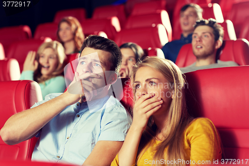 Image of happy friends watching horror movie in theater