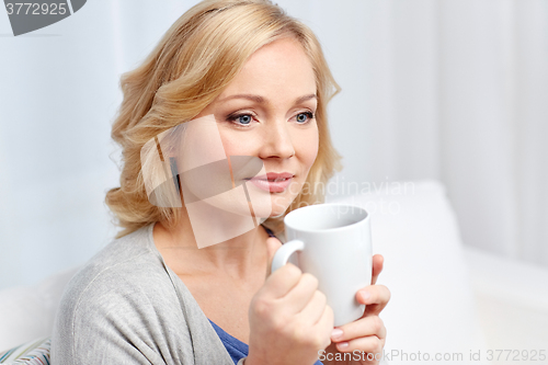 Image of smiling woman with cup of tea or coffee at home