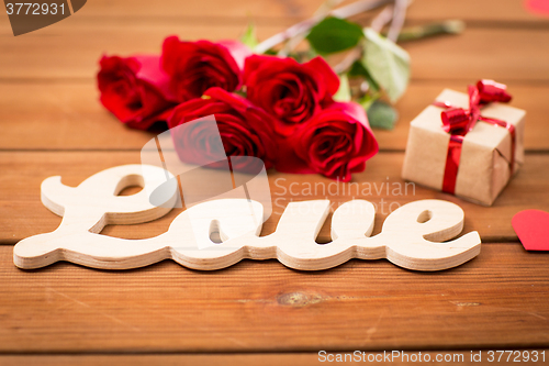 Image of close up of gift, word love, red roses and hearts