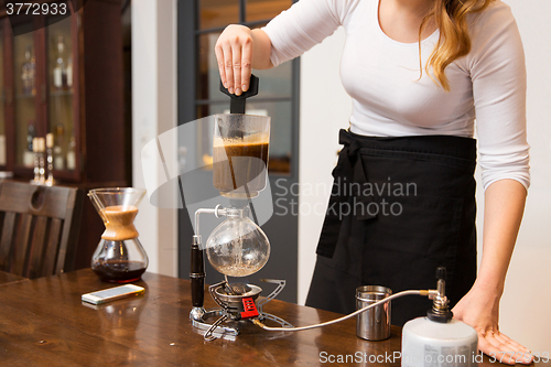 Image of close up of woman with siphon coffee maker at shop