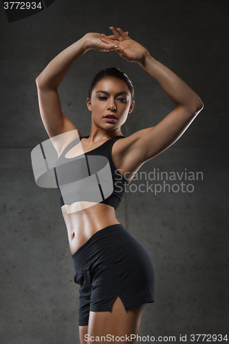 Image of young woman posing and showing muscles in gym