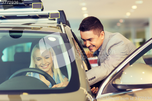 Image of happy woman with car dealer in auto show or salon