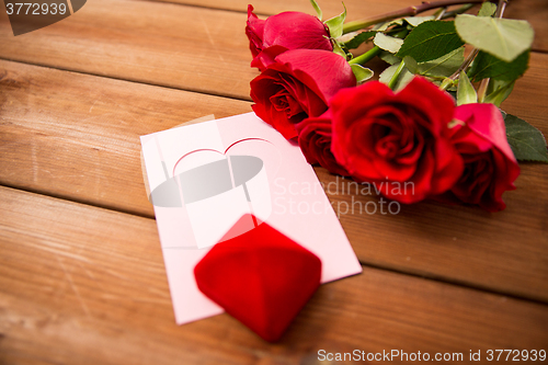 Image of close up of gift box, red roses and greeting card