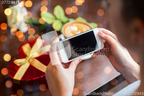 Image of close up of hands with smartphone, gift and coffee