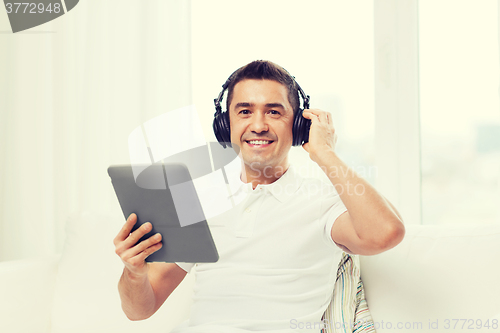 Image of smiling man with tablet pc and headphones at home