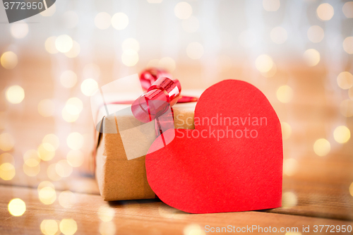 Image of close up of gift box and heart shaped note on wood