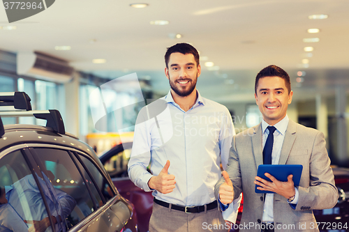Image of happy man showing thumbs up in auto show or salon