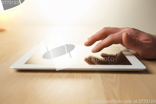 Image of The tablet with the hand on wooden table