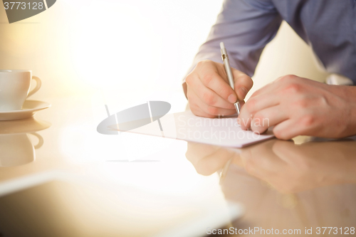 Image of The male hands with a pen and the cup