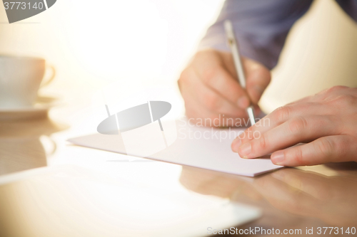 Image of The male hands with a pen and the cup