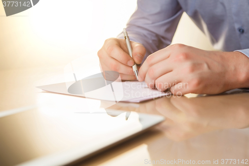 Image of The male hands with a pen and the cup