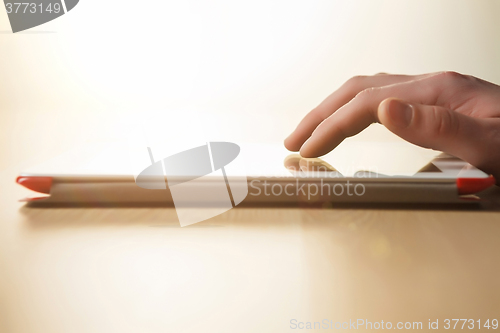 Image of The tablet with the hand on wooden table