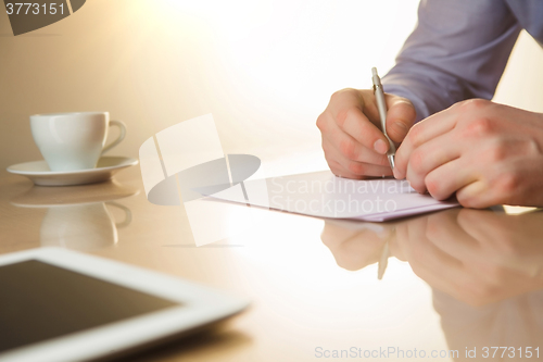 Image of The male hands with a pen and the cup