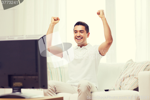 Image of smiling man watching sports at home