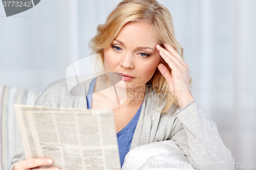 Image of woman reading newspaper at home