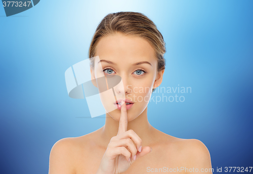 Image of beautiful young woman holding finger on lips