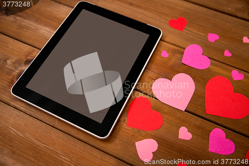 Image of close up of tablet pc and hearts on wood