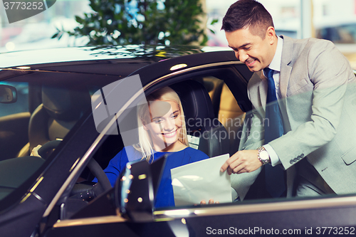 Image of happy woman with car dealer in auto show or salon