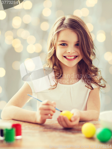 Image of close up of girl with brush coloring easter eggs