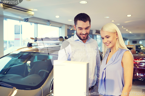 Image of happy couple buying car in auto show or salon