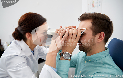 Image of optician with pupilometer and patient at eye clinic