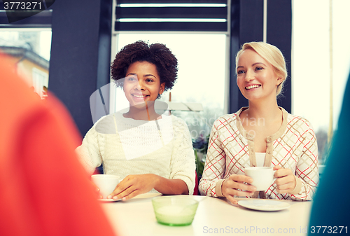 Image of happy young women drinking tea or coffee at cafe