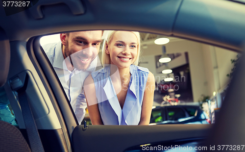 Image of happy couple buying car in auto show or salon