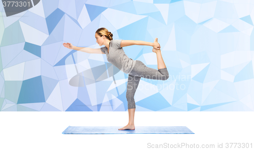 Image of woman making yoga in lord of the dance pose on mat