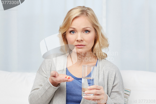 Image of woman with medicine and water glass at home