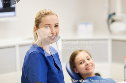 Image of happy female dentist with patient girl at clinic