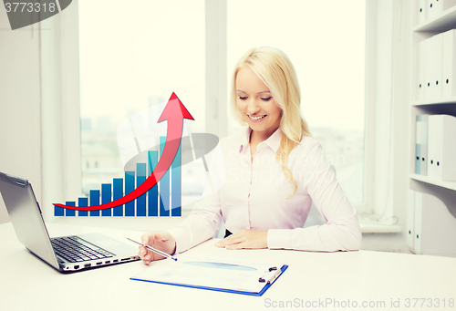 Image of smiling businesswoman with laptop and papers