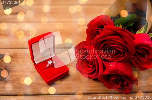 Image of close up of diamond engagement ring and red roses