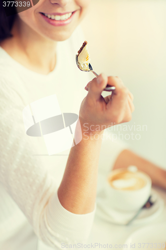 Image of close up of woman eating cake at cafe or home