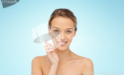 Image of happy young woman applying cream to her face