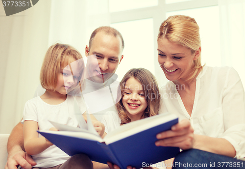 Image of smiling family and two little girls with book