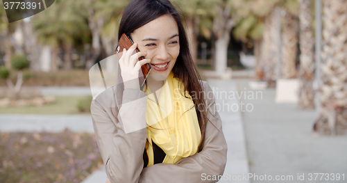 Image of Young woman standing talking on her mobile phone